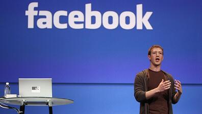 Mark Zuckerberg gives a speech against a blue Facebook backdrop.
