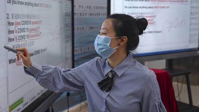 Chinese woman writes on video whiteboard in presentation setting