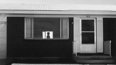 black and white picture - a lone silhouette in the window of a house