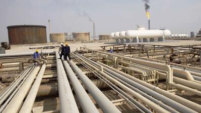 Iraqi workers walk on pipelines of an oil refinery near the city of Basra in 2009
