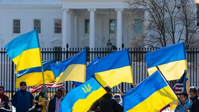 People waving Ukrainian flags in front of the White House