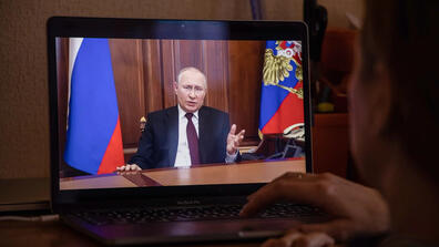 A person watching Vladimir Putin speak on their laptop