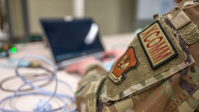 A person sitting in a uniform with a laptop