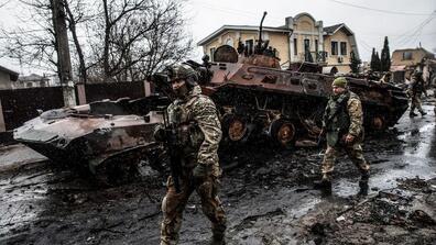 Ukrainian soldiers walk along a road littered with destroyed Russian tanks, armored vehicles and other equipment in a residential neighborhood in Bucha, Ukraine, on April 3.