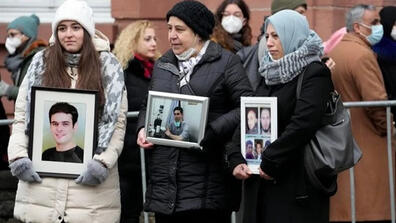 From left, Syrian women Samaa Mahmoud, Mariam Alhallak and Yasmen Almashan hold pictures of relatives who died in Syria, before the verdict in front of the court in Koblenz, Germany, Jan. 13, 2022