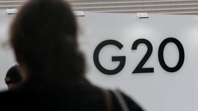 A person looking at a wall that says G20 on it