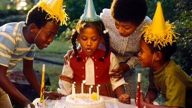 a child blows out candles on a birthday cake