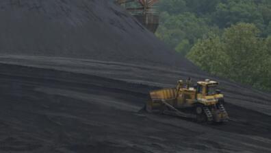 A truck on a large field of black coal.