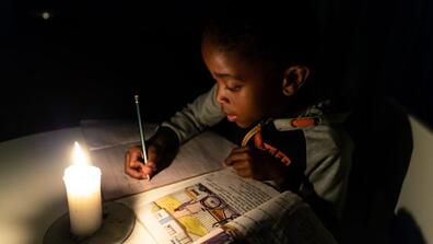 A Zimbabwean boy does his homework by candlelight in Harare