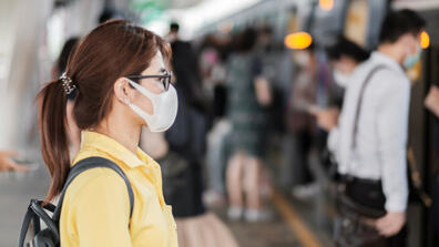 A woman waiting to get in the train with her mask on
