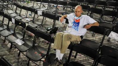 David Turk sits in a chair surrounded by empty seats at the 2008 DNC.