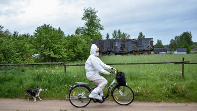 A person cycling wearing a covering suit and a mask