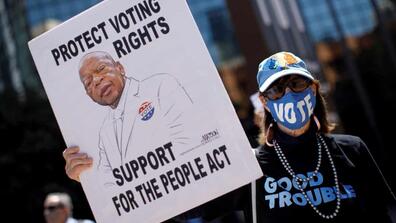 a protestor holds up a pro-voting sign with the image of John Lewis