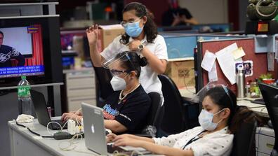 workers wearing masks type on their laptops