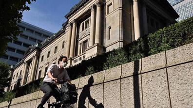 asian man riding bicycle in front of government building 