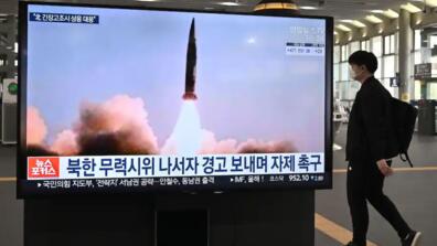 A man walks past a television screen at Suseo railway station in Seoul on March 26 showing news footage of North Korea's latest tactical guided missile test