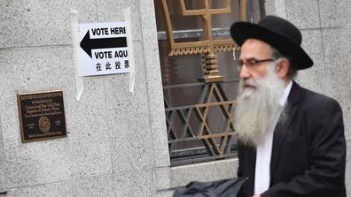 An Orthodox Jewish man walks toward a voting sign