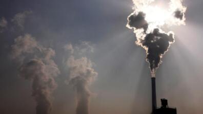 A coal-burning power plant can be seen behind a factory in the city of Baotou in China on October