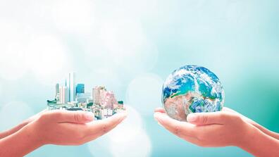 one pair of hands holds a cityscape and another pair of hands holds an Earth