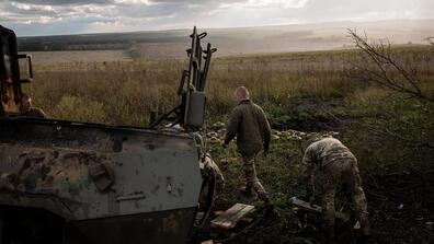 2 men next to a tank in a field