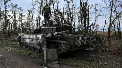 ukrainian soldier on top of abandoned russia tank