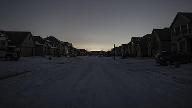 A snowy suburban street in Texas where all the lights are out.