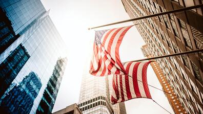american flags hang from the side of skyscrapers