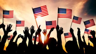 silhouettes of people wave american flags