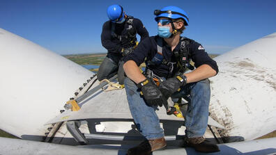 two workers work on a wind turbine