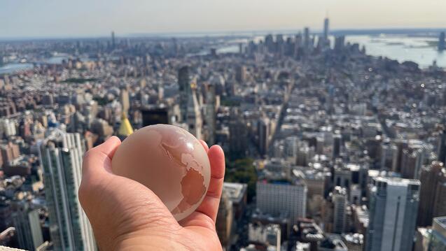 Person holding globe over NYC