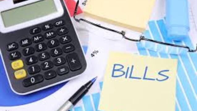 calculator, glasses, and post-it note with word "BILLS" 