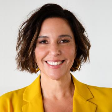 Headshot of Daniela Campello in a yellow blazer against a white background.
