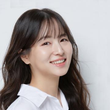 Headshot of a smiling Jiyoon Kim with long dark wavy hair, wearing a white collared shirt.