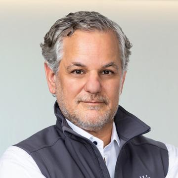 Headshot of Evan Wolff wearing a gray vest over a white shirt.