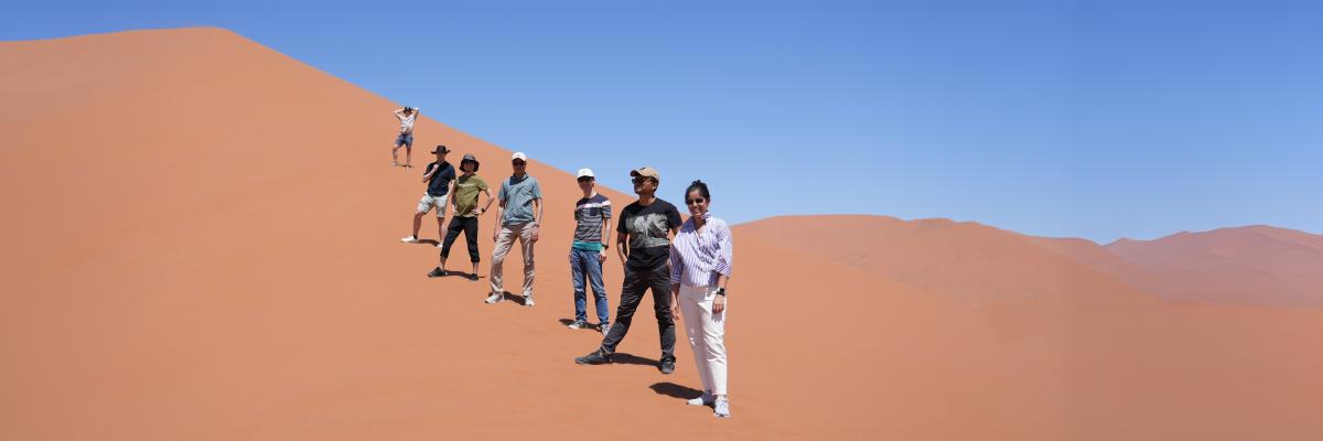 A group of Capstone students posing along the ridge of a larged sand dune in Namibia