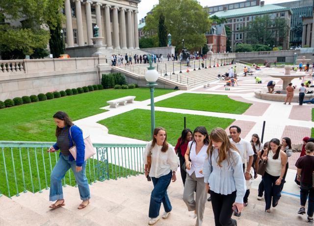 Students walking up steps on the Columbia University campus, with Low Library in the background.